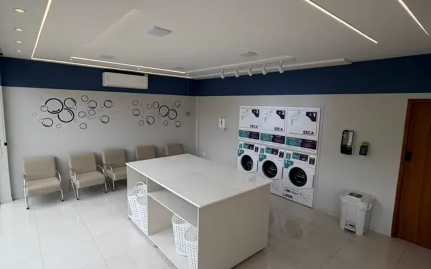Salão do autoatendimento da LavMania em Vitória da Conquista, com mesa central e cestos